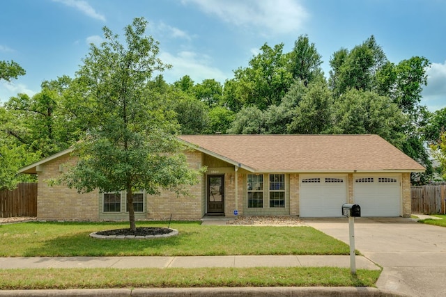 ranch-style home with fence, an attached garage, a front lawn, brick siding, and driveway