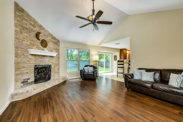 living area with high vaulted ceiling, a ceiling fan, wood finished floors, and a brick fireplace