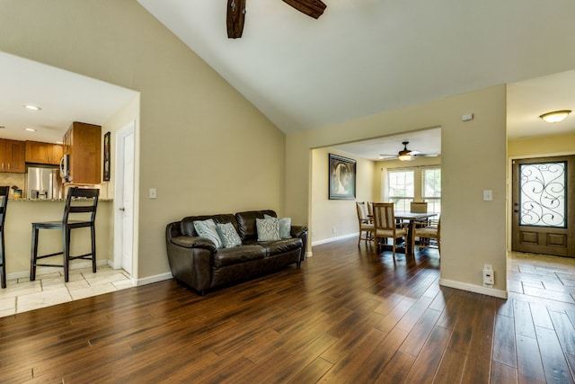 living area with baseboards, light wood finished floors, ceiling fan, and vaulted ceiling