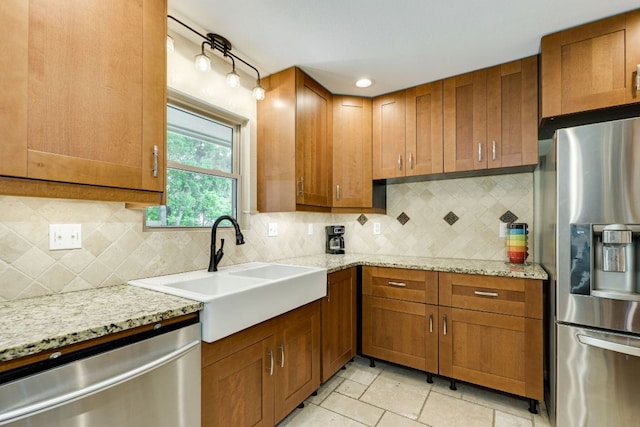 kitchen featuring brown cabinetry, a sink, decorative backsplash, and stainless steel appliances