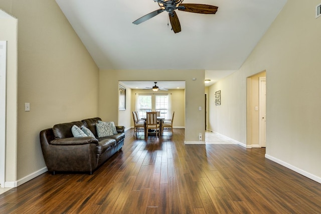 living room featuring baseboards, ceiling fan, vaulted ceiling, and dark wood-style floors