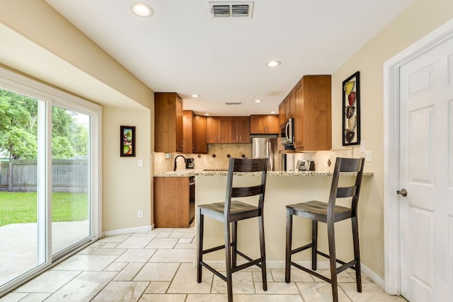 1307 S Meadows Dr, Austin, TX 78758 - kitchen featuring stainless steel appliances, brown cabinetry, baseboards, recessed lighting, and tasteful backsplash