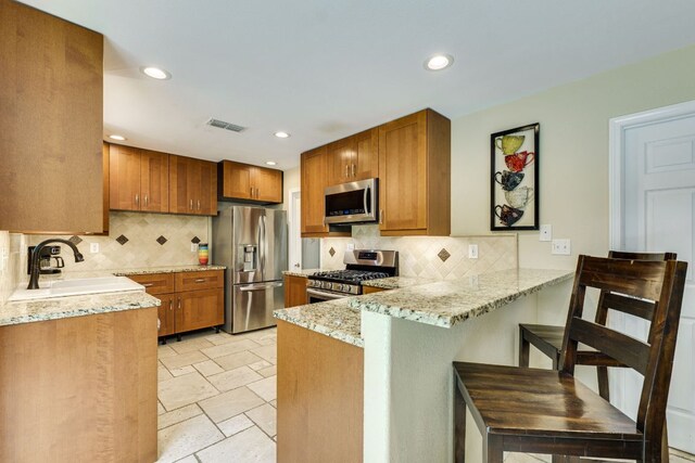 1307 S Meadows Dr, Austin, TX 78758 - kitchen with appliances with stainless steel finishes, a sink, a peninsula, brown cabinets, and light stone counters