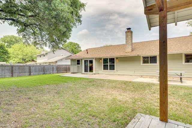 back of property featuring a chimney, roof with shingles, a fenced backyard, a yard, and a patio