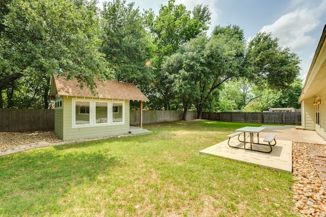 view of yard featuring an outbuilding, a fenced backyard, and a patio area