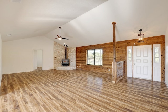 unfurnished living room with ceiling fan, lofted ceiling, light wood-style flooring, and a wood stove