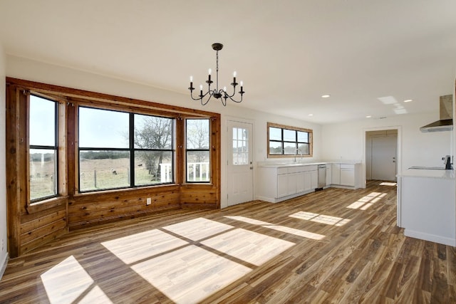 unfurnished dining area with a sink, recessed lighting, wood finished floors, and a chandelier