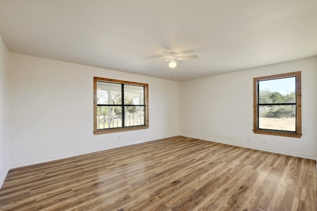 spare room featuring plenty of natural light, a ceiling fan, baseboards, and wood finished floors