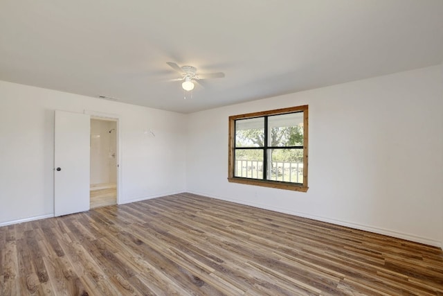 empty room featuring visible vents, a ceiling fan, baseboards, and wood finished floors