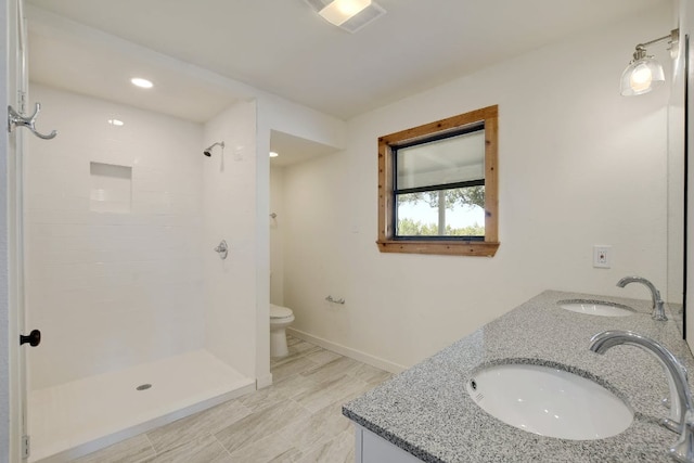 full bathroom with double vanity, a sink, and toilet