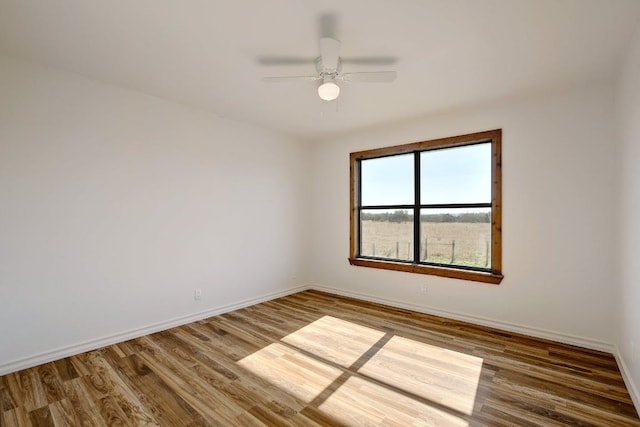 empty room with baseboards, ceiling fan, and wood finished floors