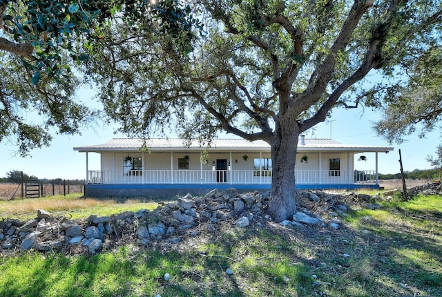 view of front facade featuring fence, a porch, and metal roof