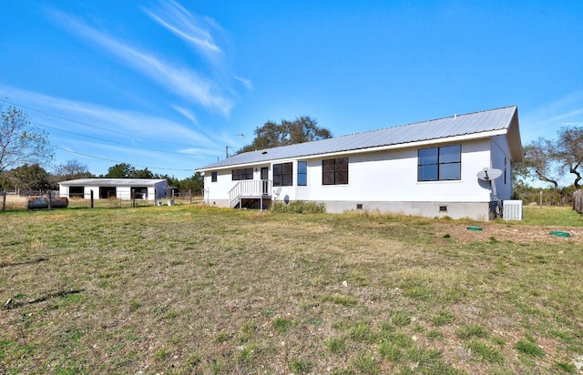 back of house featuring fence, central AC, crawl space, a lawn, and metal roof