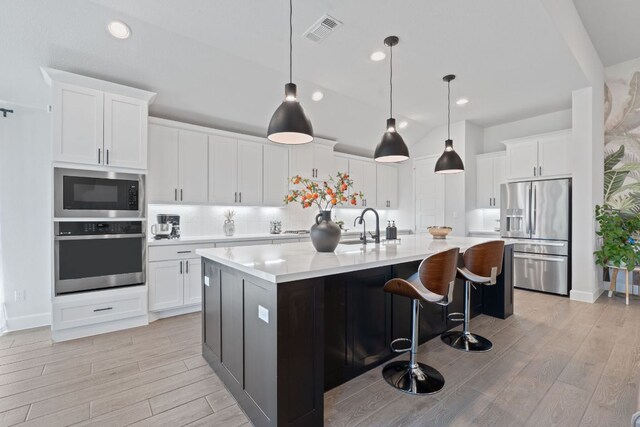 1504 Caylea Bluff Ln, Georgetown, TX 78628 - kitchen with stainless steel appliances, light countertops, light wood-style flooring, white cabinetry, and lofted ceiling