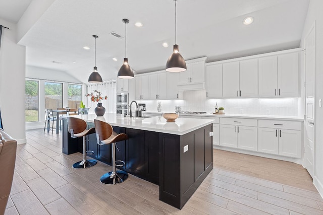 1504 Caylea Bluff Ln, Georgetown, TX 78628 - kitchen with light wood-style flooring, appliances with stainless steel finishes, light countertops, lofted ceiling, and white cabinetry