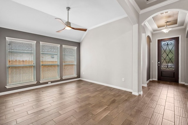 foyer entrance featuring crown molding, arched walkways, a ceiling fan, baseboards, and wood finished floors