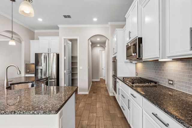 kitchen with dark wood-style flooring, a sink, arched walkways, stainless steel appliances, and visible vents
