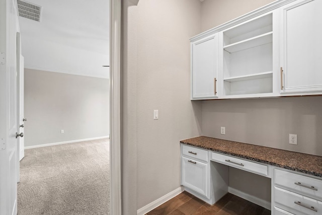unfurnished office with baseboards, visible vents, and built in desk