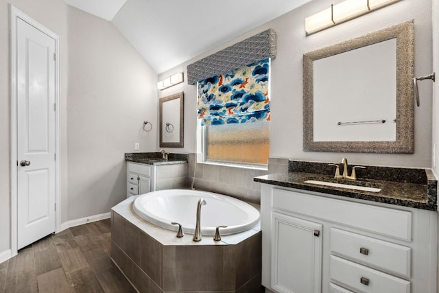 full bath featuring a sink, a bath, lofted ceiling, and two vanities