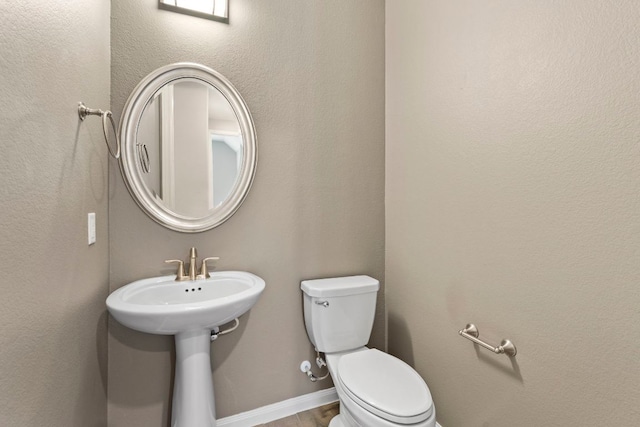half bathroom with toilet and wood finished floors
