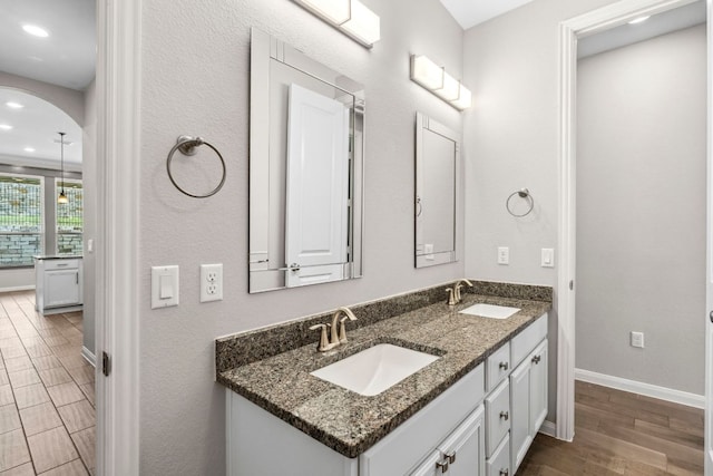 bathroom with baseboards, a sink, wood finished floors, and double vanity
