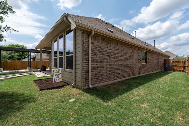 view of home's exterior with a fenced backyard, a yard, roof with shingles, and brick siding