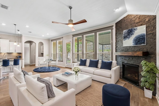 12509 Morelia Way, Austin, TX 78748 - living area featuring visible vents, a ceiling fan, a stone fireplace, light wood-type flooring, and arched walkways
