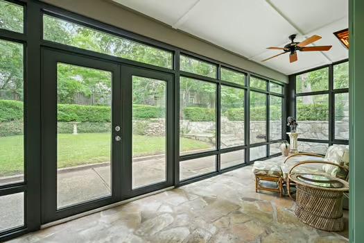 sunroom with stone finish floor, ceiling fan, floor to ceiling windows, and french doors
