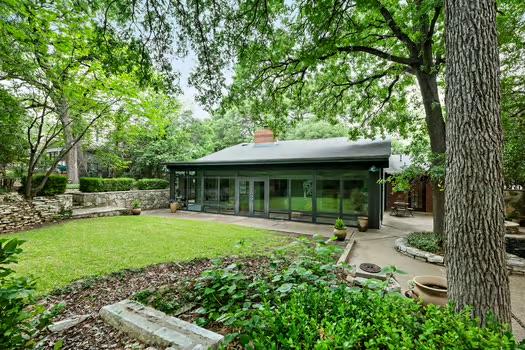 rear view of property with a yard, a chimney, a sunroom, and a patio area