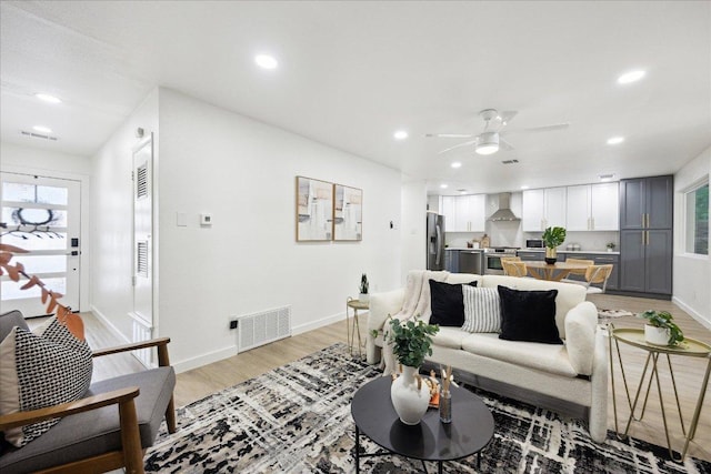 living area with light wood-style floors, plenty of natural light, a ceiling fan, and visible vents