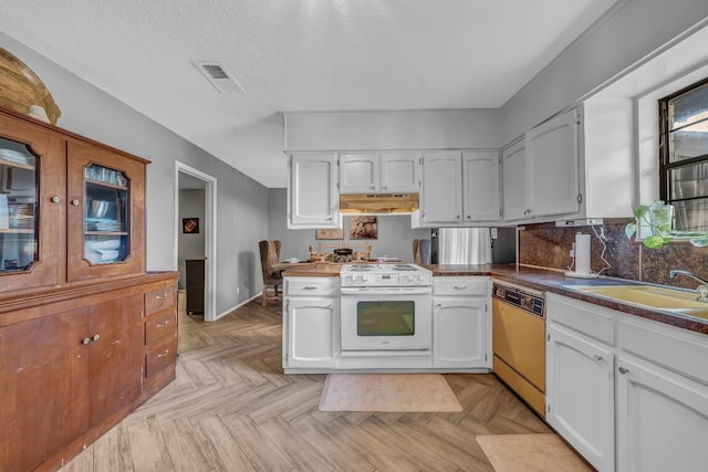 9623 County Road 347, Caldwell, TX 77836 - kitchen with white cabinets, dishwasher, white range with gas stovetop, under cabinet range hood, and visible vents