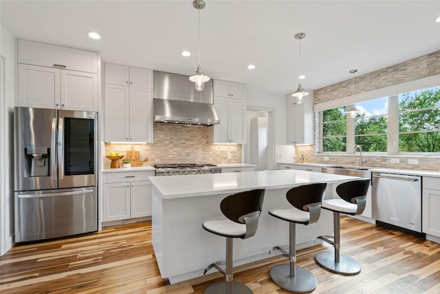 2902 Cedarview Dr, Austin, TX 78704 - kitchen with a center island, light countertops, light wood finished floors, stainless steel appliances, and wall chimney exhaust hood