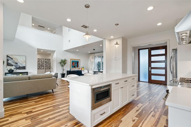 2902 Cedarview Dr, Austin, TX 78704 - kitchen with stainless steel fridge, light countertops, built in microwave, white cabinets, and light wood-style flooring