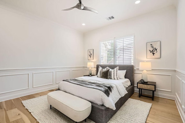 bedroom featuring visible vents, recessed lighting, wainscoting, and a decorative wall