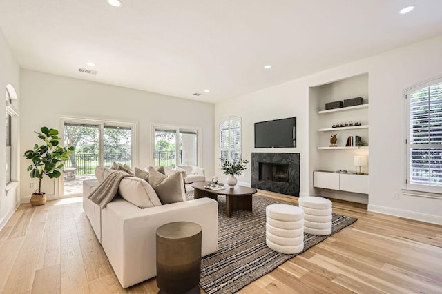 living area with visible vents, recessed lighting, a premium fireplace, and light wood-type flooring