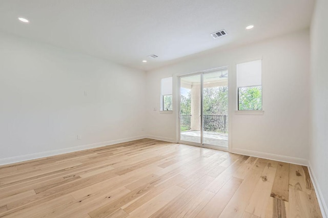empty room featuring baseboards, visible vents, a healthy amount of sunlight, and light wood-style floors