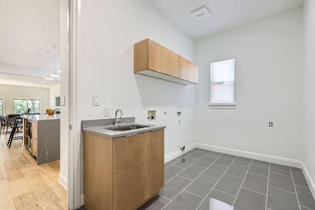 clothes washing area featuring hookup for a gas dryer, cabinet space, a sink, baseboards, and hookup for a washing machine