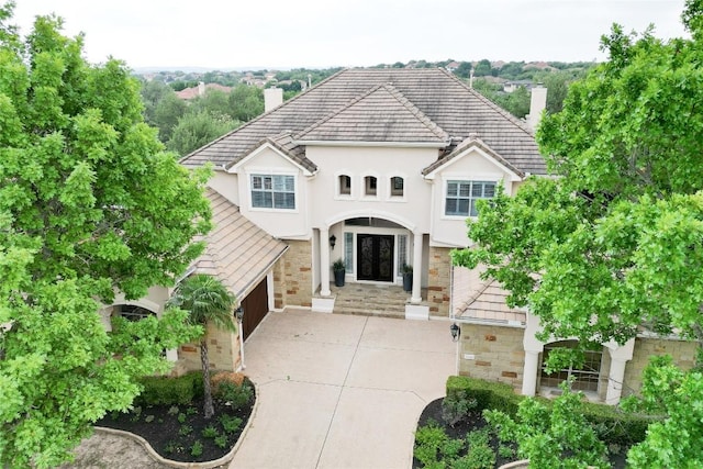 view of front of property featuring a chimney, concrete driveway, stucco siding, and stone siding