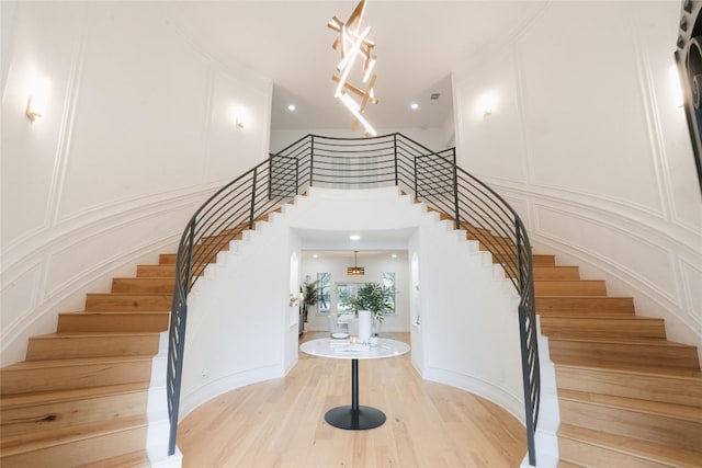 staircase with wood finished floors, a high ceiling, and a decorative wall