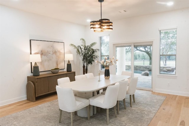 dining room with baseboards, visible vents, light wood-style flooring, and a notable chandelier