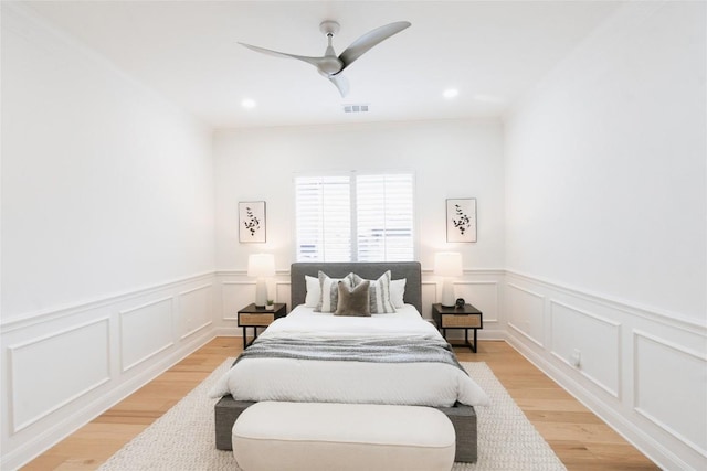 bedroom with wainscoting, a decorative wall, and visible vents