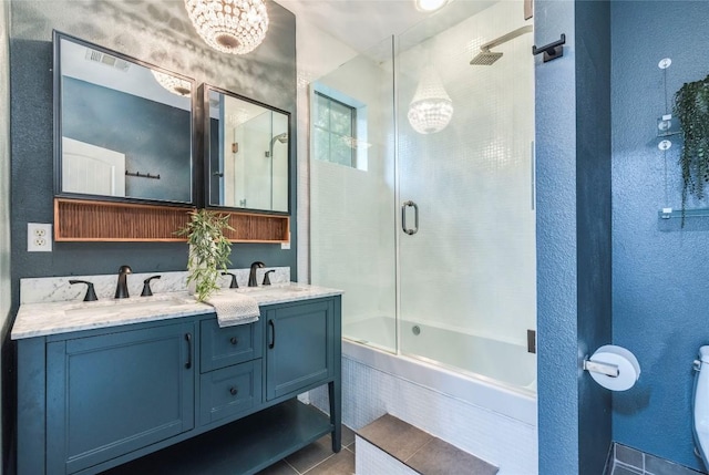full bath with a sink, a textured wall, toilet, and double vanity