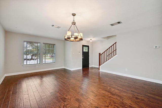 interior space with an inviting chandelier, visible vents, stairway, and dark wood-style floors
