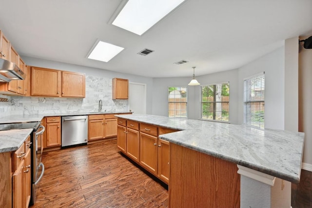 kitchen featuring exhaust hood, appliances with stainless steel finishes, a sink, dark wood finished floors, and visible vents