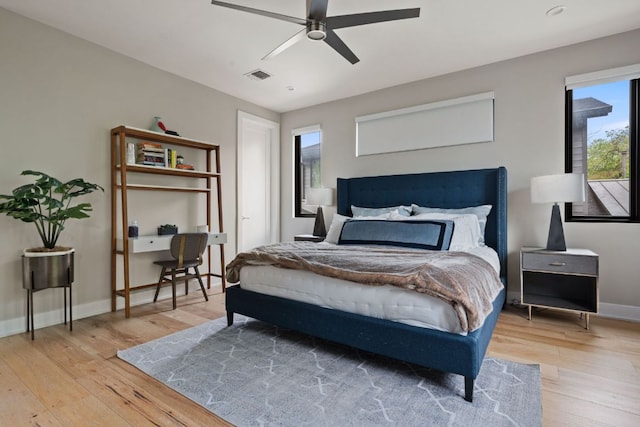 bedroom featuring baseboards, visible vents, ceiling fan, and light wood finished floors