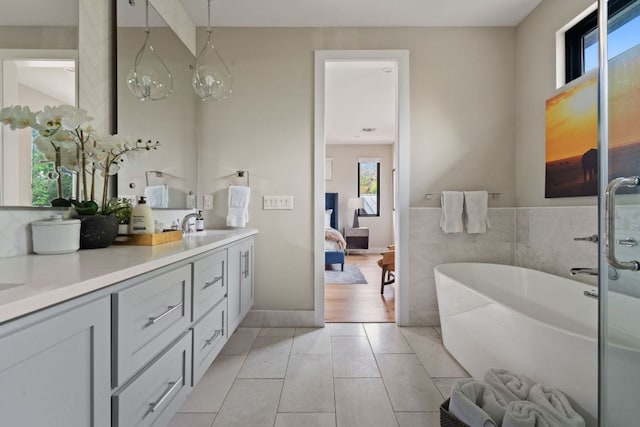ensuite bathroom with double vanity, tile patterned floors, a soaking tub, and ensuite bath