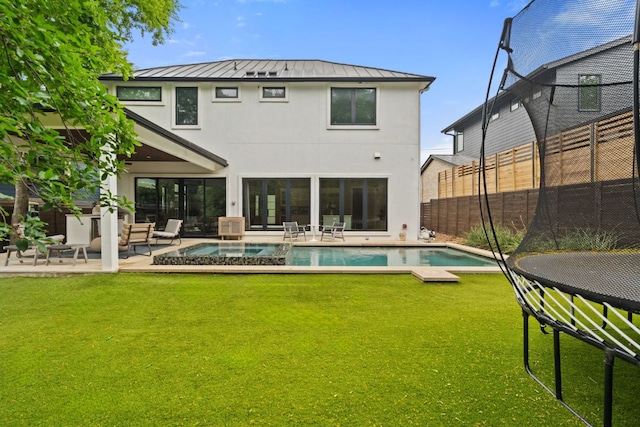 back of property with stucco siding, a patio area, a standing seam roof, a lawn, and fence private yard