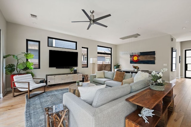 living area featuring light wood-type flooring, a ceiling fan, baseboards, and visible vents