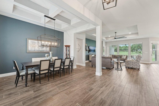 dining area featuring a raised ceiling, coffered ceiling, and wood finished floors