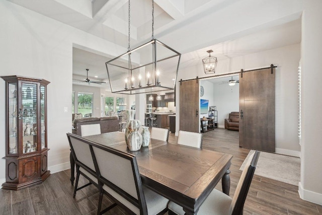 dining room featuring baseboards, a barn door, ceiling fan with notable chandelier, and wood finished floors